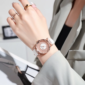 Close-up of rose gold watch with sparkling crystals and white leather strap on wrist