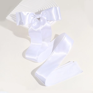 Detail of elegant white silk bow hair clip with long ribbons on a wavy backdrop