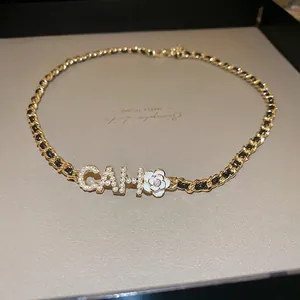 Gold-plated woven chain necklace featuring a white camellia and pearl-inlaid letters
