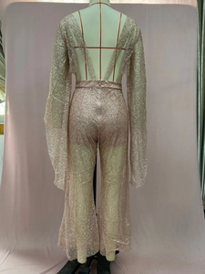Detail of sequined rose gold jumpsuit with deep V-back and wide flared trousers