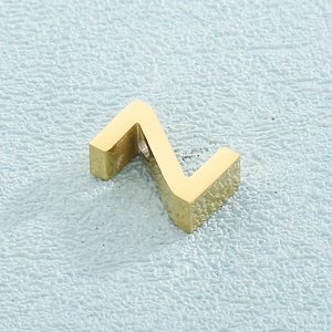 Detailed macro shot of a polished gold letter Z charm pendant on blue background