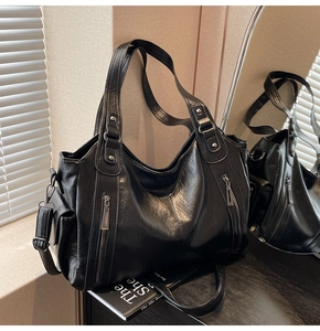 Detailed view of black leather tote bag featuring silver zipper and grainy texture