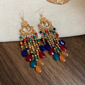 Macro detail of Bohemian beaded drop earrings with colorful tassels on linen background