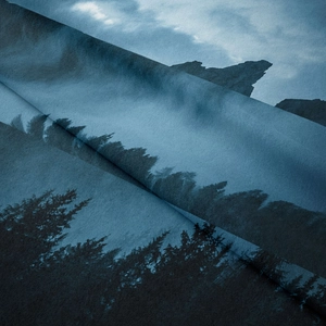 Close-up of soft polyester fabric showing blue mountain forest print and smooth texture