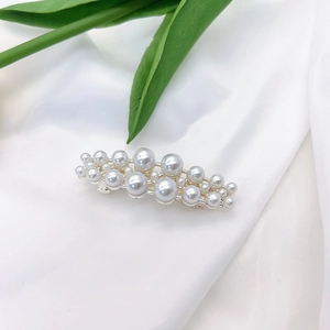 Close-up of elegant pearl hair clip with silver metal base on white silk fabric