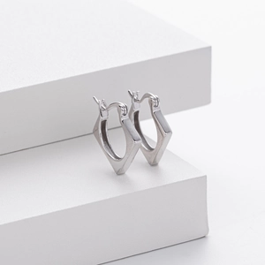 Detailed view of silver square geometric huggie earrings on a white minimalist platform