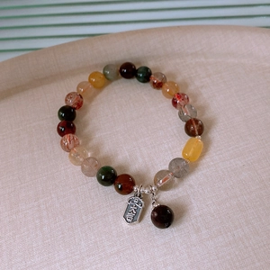 Detailed macro view of multicolor natural stone beads with a silver Da Ji lucky charm pendant