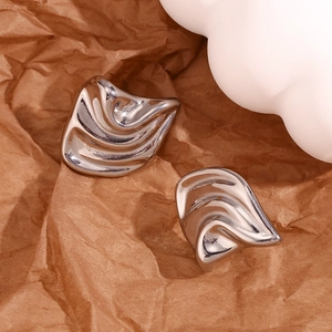 Close-up of abstract wavy silver irregular earrings on a rustic brown paper background