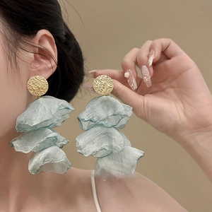Close-up of tiered chiffon flower tassels and hammered gold metal studs on ear