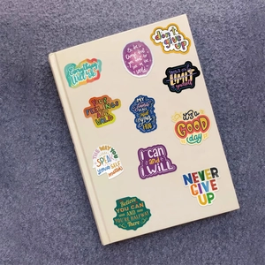 Close-up of motivational quote stickers applied on a beige notebook cover