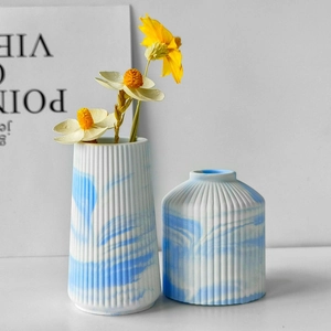 Close-up of blue and white marble textured ceramic vases with vertical stripe relief