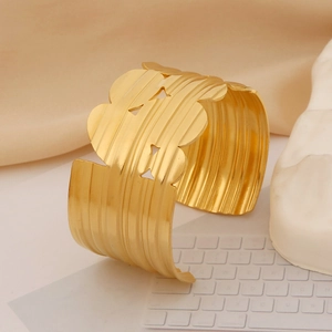 Detail of gold wide cuff bracelet with vertical hammered texture and geometric cutouts