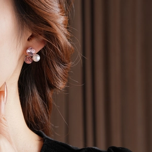 Close-up of elegant triangular earrings with pink crystals and pearls worn by a model