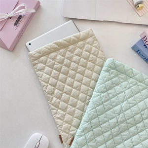 Detail of quilted tablet sleeve in beige and mint green showing inner storage capacity