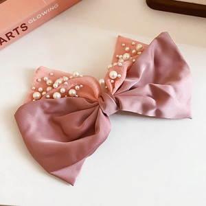 Macro detail of pink satin and tulle hair clip with white pearls and bow design