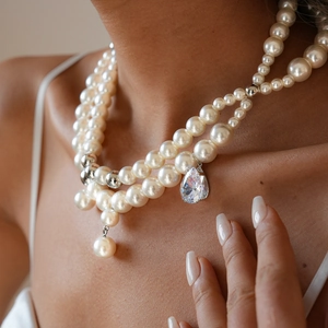 Close-up of elegant multi-layered pearl necklace with large teardrop zircon pendant