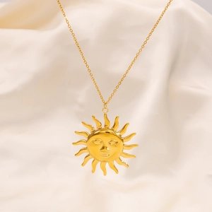 Macro shot of 18k gold plated sun face pendant necklace on soft pleated fabric background