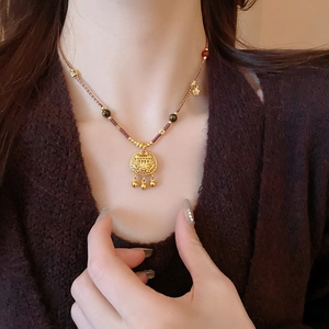 Dettaglio della collana rossa intrecciata con ciondolo lucchetto e piccoli campanelli