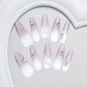 Press-on nails with purple cat eye gradient effect and rhinestones on a mirror tray