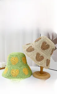 Detail of hand-crocheted paper straw bucket hats with hollow-out heart patterns