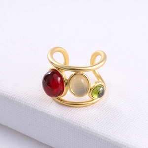 Adjustable gold ring featuring red, green, and white crystals on textured surface