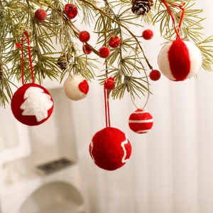 Red and white wool felt Christmas balls hanging on pine branches with festive ornaments