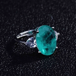 Macro view of oval green gemstone ring with pear-shaped side diamonds and silver band