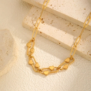 Elegant gold heart paperclip chain necklace for women displayed on a travertine stone background