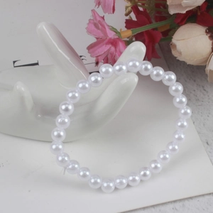 Detail of white round faux pearl bracelet displayed on a white ceramic hand stand