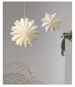 Detail of warm LED lighted paper snowflake and star pendants for holiday interior decor
