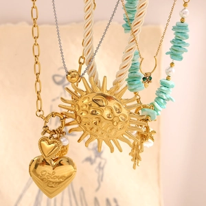 Close-up of layered 18K gold-plated necklaces with sun pendant and I Love You heart