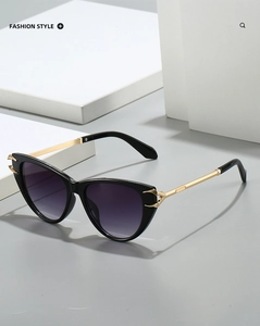 Detail of fashion cat-eye sunglasses with gold metal hinges and black gradient lenses