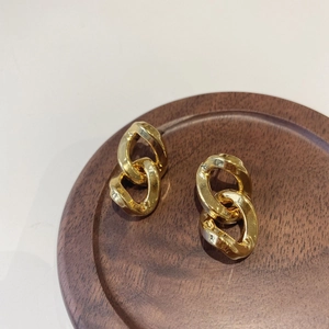 Macro shot of gold-plated thick chain link earrings on a dark wood tray display