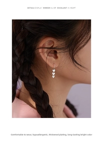 Detail of silver triple heart drop earrings with high mirror finish on female model