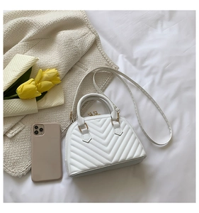 Close-up of white chevron quilted seashell handbag with gold hardware and shoulder strap
