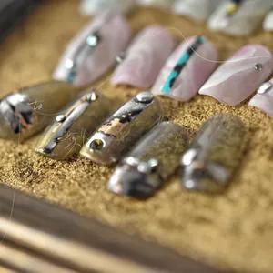 Detailed macro view of pink marble nail stickers with metallic lines and gemstone accents