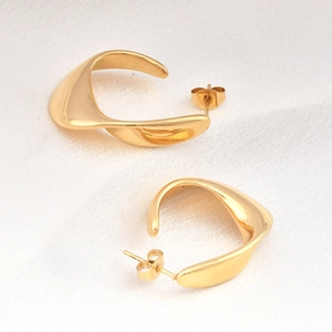 Minimalist gold-plated stainless steel twisted hoop earrings on white silk background