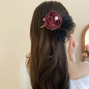 Close-up of hair clip with burgundy rose, black lace, and hanging pearl tassels on hair