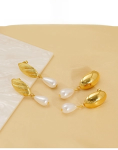 Macro detail of 18K gold titanium steel earrings with irregular pearls on marble stand