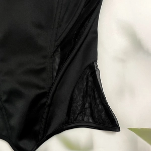 Detailed close-up of the black satin corset top featuring sheer mesh side panels