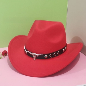 Detail of red cowboy hat featuring black band with silver studs and bull head metal piece