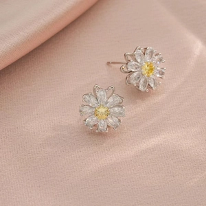 Detailed macro view of daisy earrings with yellow zircon center on pink silk fabric