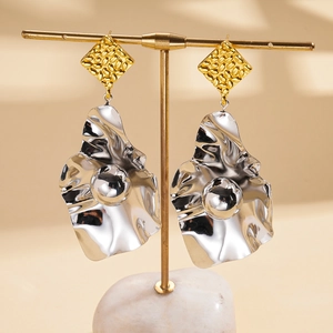 Detail view of irregular wavy silver metal drop earrings with gold textured diamond studs