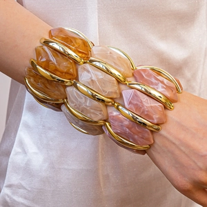Détail de bracelets en résine ambre et beige avec cadres dorés sur le poignet