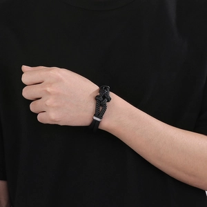 Detail of black braided leather bracelet with silver knot and magnetic clasp on wrist