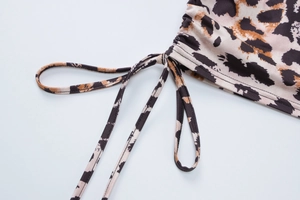 Detailed close-up of leopard print fabric with side drawstring design on the skirt