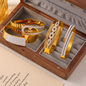 Ensemble de bracelets dorés asymétriques avec diamants dans une boîte à bijoux en bois chic