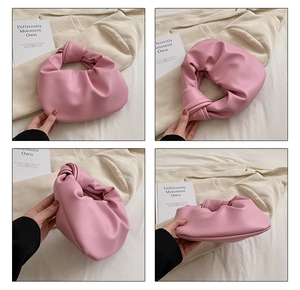 Detail view of pink crescent bag showing knotted handle and soft pleated texture