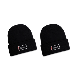 Two black knitted beanies featuring My Love battery embroidery in a flat lay style
