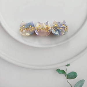 Detailed view of three cute acetate cat hair clips with marble texture on ceramic plate